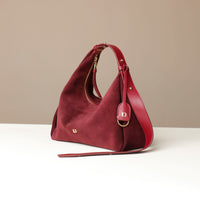 red suede leather danilos handbag with gold accents on a beige background