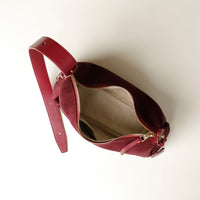 red suede leather danilos handbag with a gold zipper on a white background