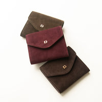 Three suede danilos wallets envelope shape in red, green, brown colors on a white background
