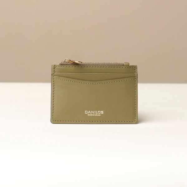 front view of a nappa leather card case nirua in olive green brown with gold accents over a beige background