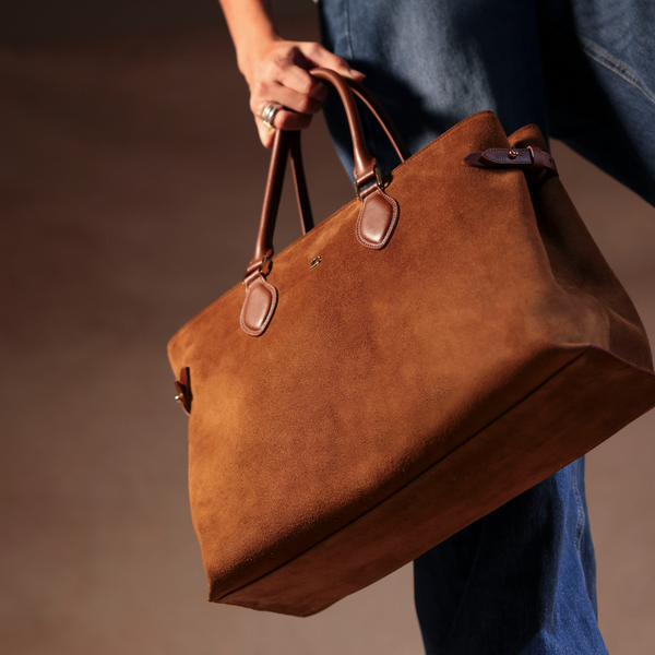 Brown suede leather danilos handbag held by a person against a neutral background