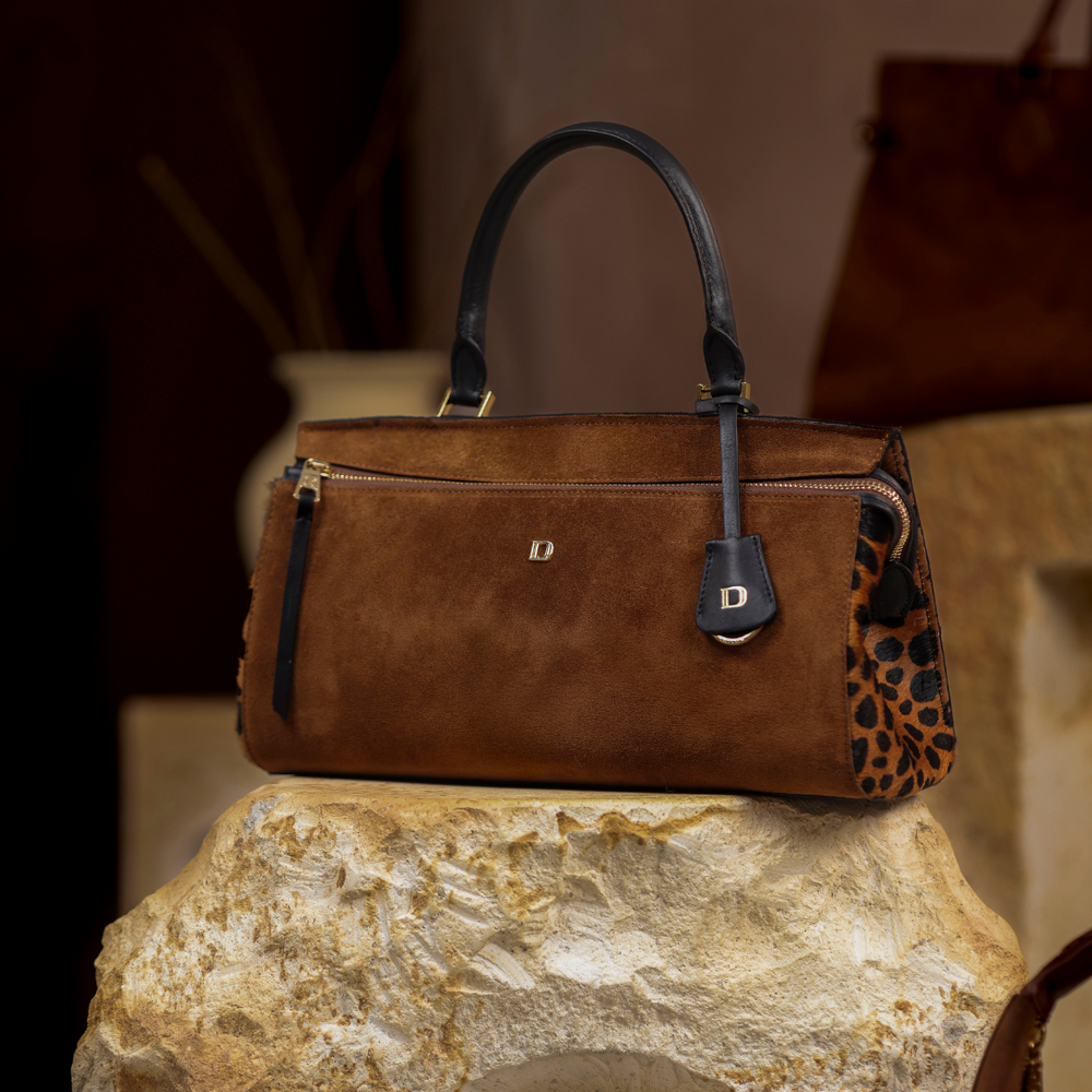 Brown leather Danilos handbag with a leopard print detail on a stone surface