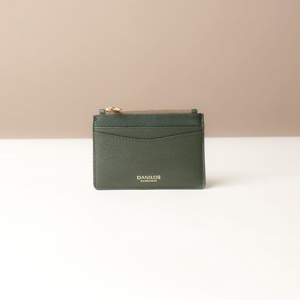front view of a nappa leather card case nirua in emerald green brown with gold accents over a beige background