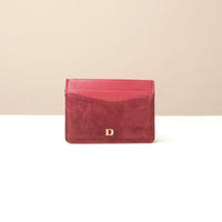 red uede leather cardholder with a gold Danilos logo on a beige background