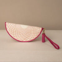 half-circle clutch Agnes made with natural fiber and mahenta leather details, with leather strap and tassel, front view