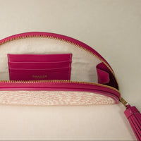 An open half-circle clutch Agnes made with natural fiber and mahenta leather details, with leather strap and tassel, upper view