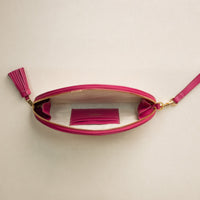 And open clutch Agnes made with natural fiber and mahenta leather details, with leather strap and tassel, upper view.