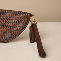 Close-up of a clutch Agnes made with raffia and palisander, brown leather details, with leather strap and tassel, front view
