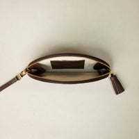 And open clutch Agnes made with raffia and palisander, brown leather details, with leather strap and tassel, with three slots for credit cards. Gold hardware. Upper view.
