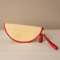 half-circle clutch Agnes made with raffia rot and red leather details, with leather strap and tassel, front view
