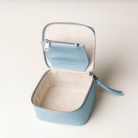 upper view of an open small leather Danilos Jewelry Organizer Anushka in light blue with embossed text on a beige background