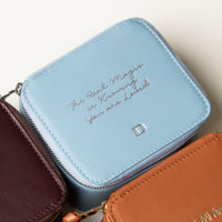 close up view of a small leather Danilos Jewelry Organizer Anushka in light blue with embossed text on a beige background