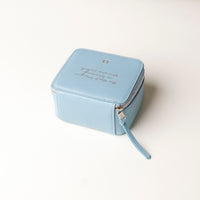 back view of a small leather Danilos Jewelry Organizer Anushka in light blue with embossed text on a beige background