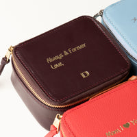 close-up view of a small leather Danilos Jewelry Organizer Anushka in dark brown with embossed gold text on a white background