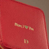 Close-up view of a small leather Danilos Jewelry Organizer Anushka in red with embossed gold text on a white background