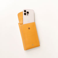 front view of a open yellow danilos leather multi smartphone alessia with a phone inside a pocket over a white background