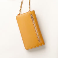 back view of a yellow danilos leather multi smartphone alessia with a gold zipper pocket and chain over a beige background