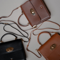Three Nelda Bag elegant leather handbag with detachable shoulder strap in brown, black, and tan on a light gray background
