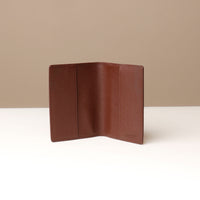 front view of a open brown pebble leather passport lovable Danilos on a light surface with a neutral background