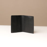 front view of a open black pebble leather passport lovable Danilos on a light surface with a neutral background