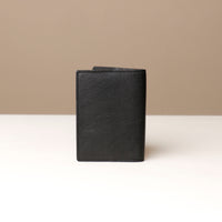 back view of a black pebble leather passport lovable Danilos on a light surface with a neutral background