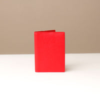 front view of a red pebble leather passport lovable Danilos on a light surface with a neutral background