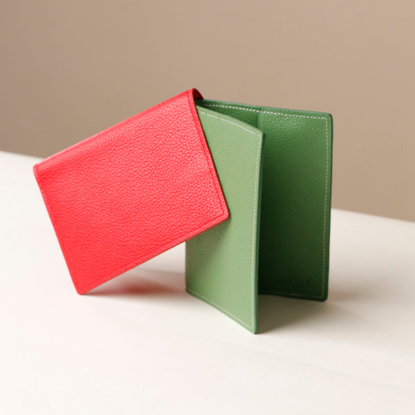Red and green pebble leather passport lovable Danilos on a light surface with a neutral background