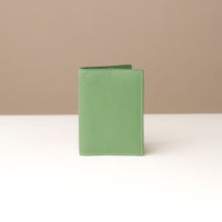 front view of a green pebble leather passport lovable Danilos on a light surface with a neutral background