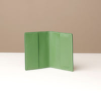 front view of a open green pebble leather passport lovable Danilos on a light surface with a neutral background