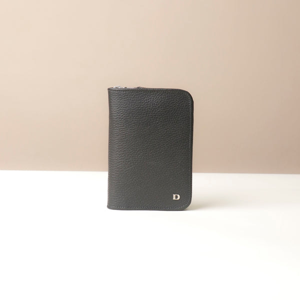 Front view of a black passport case lovable in pebble leather with a Danilos logo on a beige background