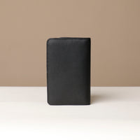 back view of a danilos travel pro passport case lux in black pebble leather in a beige background