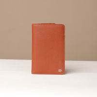 Front view of a danilos travel pro passport case lux in brown pebble leather in a beige background