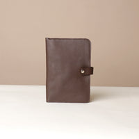 Front view of a brown Danilos pebble leather inkspirator with a clip closure on a beige background