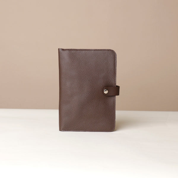 Front view of a brown Danilos pebble leather inkspirator with a clip closure on a beige background