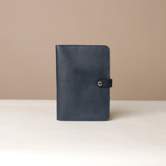 Front view of a marine blue Danilos pebble leather inkspirator with a clip closure on a beige background