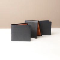 Three leather wallets in black and brown on a white surface with a beige background
