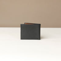 Back view of a black pebble leather Milano wallet over a beige background