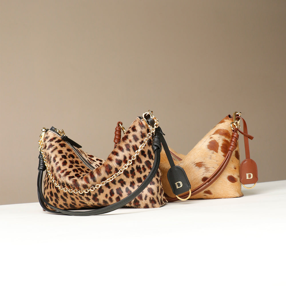 Dos bolsos, bolsos bandolera, Zeste Jr, Danilos, de piel con pelo, con estampado de leopardo y el otro con dibujo de lunares marrones, sobre fondo beige.