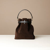 Brown bucket Danilos bag with black handle on a beige background
