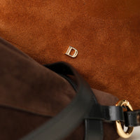 close up of a Brown suede leather bucket bag with a gold Danilos logo on a matching brown background