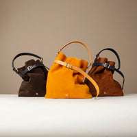 Three bucket Danilos Bags in brown, yellow, and dark brown with a strap on a neutral background.
