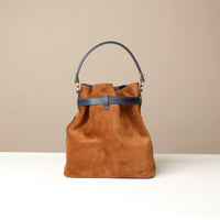 Brown suede leather bucket Danilos bag with black accents on a beige background