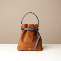Brown suede leather bucket Danilos bag with black strap on a beige background