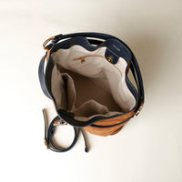 upper view of a brown suede leather bucket Danilos bag with beige interior and zipper on a light background