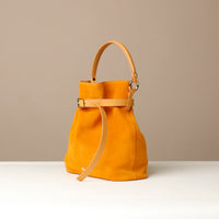 Yellow suede leather bucket Danilos bag with a strap on a beige background