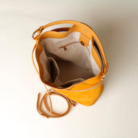 Yellow suede leather bucket Danilos bag with a strap on a light beige background