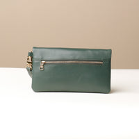 Back view of a green leather Karelia Clutch Danilos with a visible gold zipper over a white and beige background