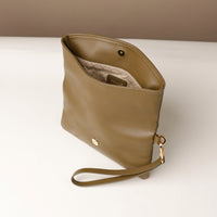 upper view of an open olive green leather Karelia Clutch Danilos with a visible hand strap over a white and beige background