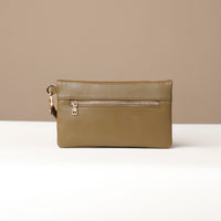 Back view of a olive green leather Karelia Clutch Danilos with a visible gold zipper over a white and beige background