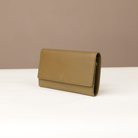 side view of a danilos clucth versaviva in olive green leather in a beige background